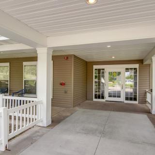 A covered entrance of a building with a porch and glass doors.