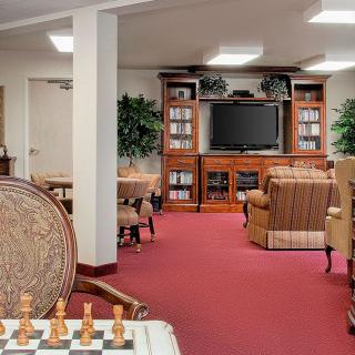 A cozy living room with a chessboard, bookshelves, and a TV.
