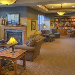 A cozy library room with comfortable seating, bookshelves, and a fireplace.