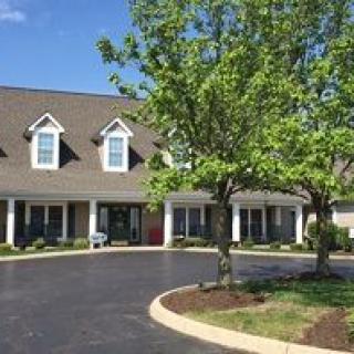 A residential building with a driveway and surrounding greenery.