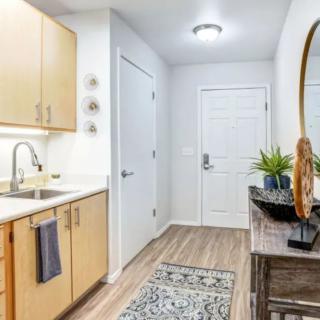 A modern kitchen and entryway with wood flooring and stylish decor.
