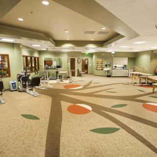 A spacious rehabilitation center featuring various exercise equipment and therapy areas.