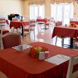 A neatly arranged dining area with tables covered in red tablecloths and decorated with autumn-themed centerpieces.