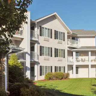 A modern apartment building with balconies and a well-maintained lawn on a sunny day.