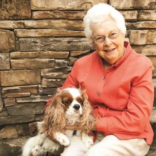An elderly woman sitting outdoors with her dog.