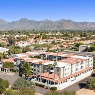 Aerial view of a residential apartment complex with mountainous landscape in the background.