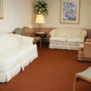 A cozy living room with white sofas, chairs, and a lamp on a red carpet.