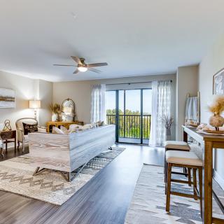 A bright and airy living room with contemporary decor, featuring a dining area, comfortable seating, and large sliding glass doors allowing abundant natural light.