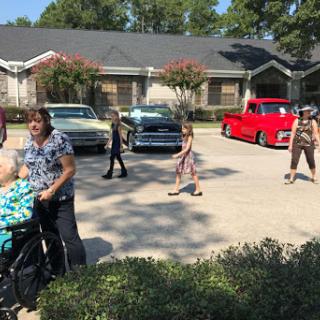 A lively family gathering in a sunny neighborhood, showcasing classic cars and joyful moments.