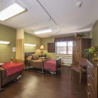 A hospital room featuring two beds, medical equipment, and warm lighting.