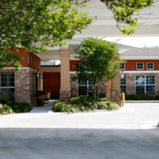 A view of a building entrance surrounded by trees and landscaping.