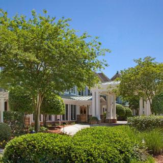 A beautiful garden with lush greenery and a house in the background under a clear blue sky.