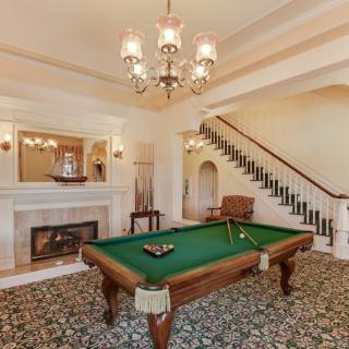 Luxurious billiard room with a pool table, fireplace, and elegant chandelier.