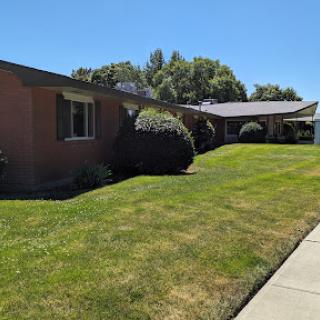 A well-maintained single-story house with a lush front yard and clear blue sky.