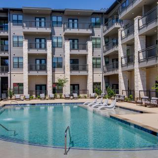 A modern apartment complex with a central swimming pool and balconies.