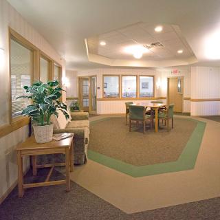 A cozy lobby area with tables, chairs, and a potted plant.