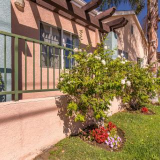 A view of a beautifully landscaped garden with vibrant flowers and a decorative fence in front of a residential building.