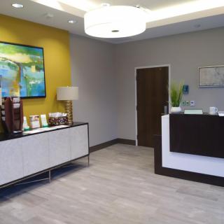 A modern and welcoming office reception area featuring a coffee station and decorative art.