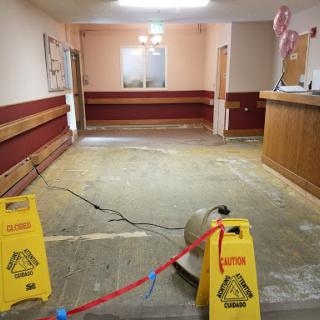 An empty waiting area undergoing renovation, with wet floor signs indicating caution.