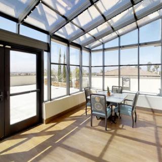 A bright and modern sunroom featuring glass walls and a cozy seating area, perfect for enjoying natural light.