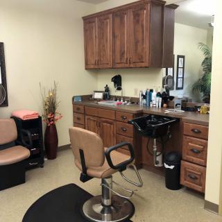 A cozy salon setup with a styling chair, mirror, and wooden cabinetry.