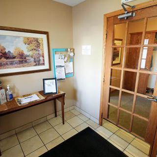 A cozy entrance foyer with a wooden door, decorated with artwork and a small table.