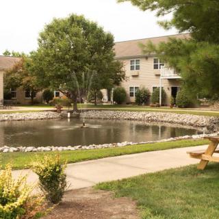 A serene courtyard with a pond surrounded by trees and buildings.