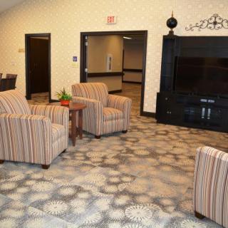 A cozy lobby area with striped armchairs, a patterned carpet, and a large television.
