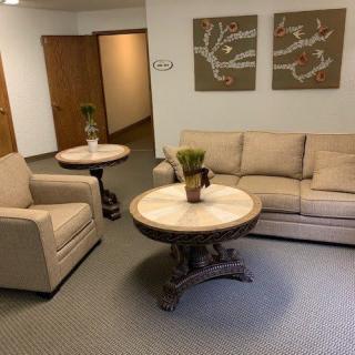 A cozy waiting room with a sofa, chair, and decorative tables.