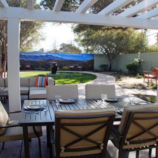 A beautiful backyard patio with a pergola, featuring a dining area and well-maintained garden.