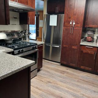 A modern kitchen with stainless steel appliances, wood cabinets, and granite countertops.