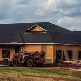A house under construction with a tractor parked in front.