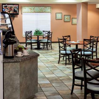 An empty cafe with neatly arranged tables and chairs, featuring a coffee station.