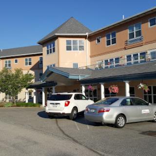A residential care facility with a welcoming entrance and parked cars.