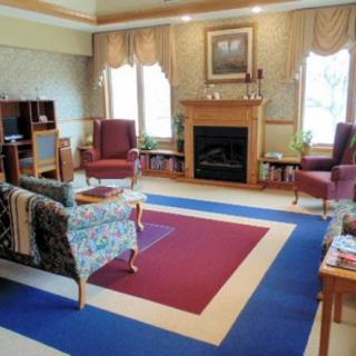 A cozy living room with a fireplace, armchairs, and decorative carpet.