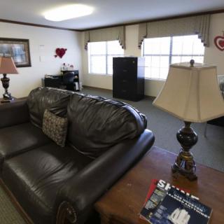 A cozy living room with a leather sofa, lamps on side tables, and large windows.