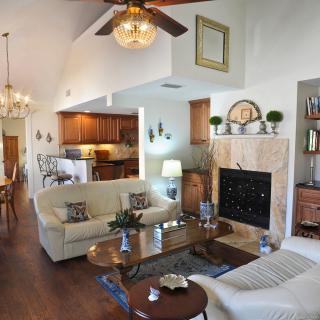 A cozy living room with a fireplace, comfortable sofas, and an open layout connecting to the kitchen and dining area.