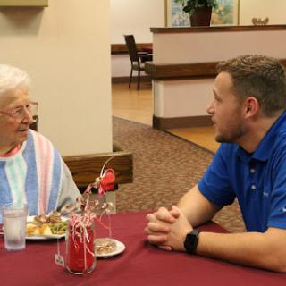 An engaging conversation between a young man and an elderly woman over dinner.