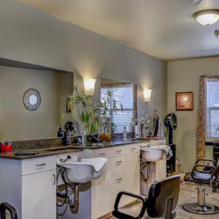A well-lit salon interior featuring styling chairs and a large mirror.