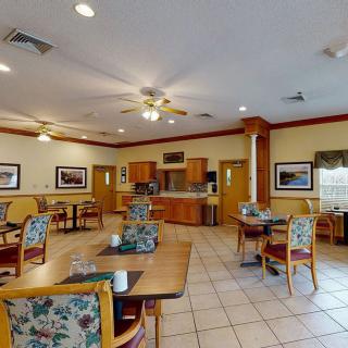 An indoor dining area with neatly arranged tables and chairs, featuring warm lighting and framed artwork on the walls.