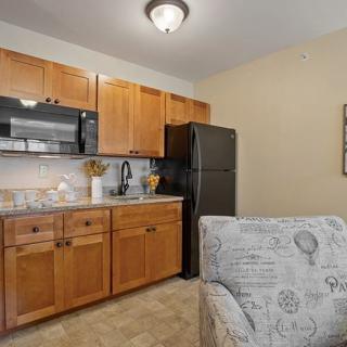 A cozy kitchen area with wooden cabinets, a microwave, refrigerator, and countertop.