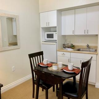Small kitchen area with a dining table and chairs, complete with a microwave and neatly arranged table settings.