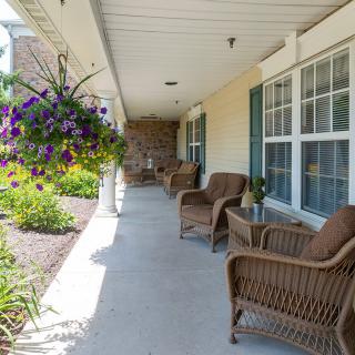 A sunny porch with wicker chairs and hanging plants.