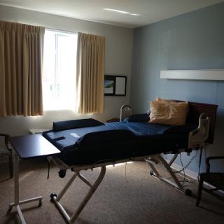 A hospital room featuring an adjustable bed, natural light from a window, and simple furnishings.