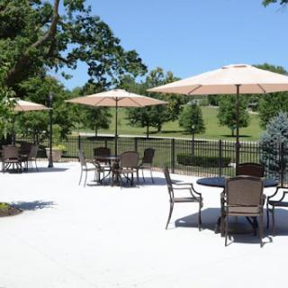 A tranquil outdoor seating area featuring tables and umbrellas, surrounded by lush greenery.