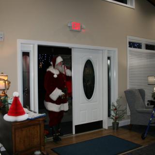 Santa Claus entering a festive room decorated for Christmas.