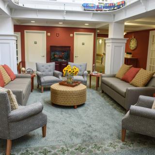 A cozy living room with several sofas and chairs arranged around a central coffee table, featuring warm lighting and tasteful decor.
