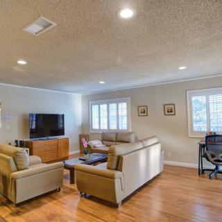 A spacious and bright living room featuring a comfortable seating area, wood flooring, and a desk.
