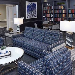 A cozy living room with blue plaid sofas, bookshelves filled with books, and stylish lamps.