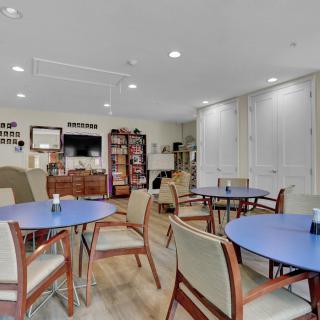 A community room with tables, chairs, and bookshelves, providing a cozy setting.